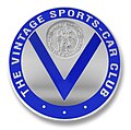 Logo du "Vintage Sports-Car Club" (club anglais de sport auto réservé aux voitures d'avant 1940). Le V de Vintage est surmonté d'un bas relief représentant Saint Christophe portant l'enfant Jésus et la phrase en français "Regarde Saint Christophe puis va-t-en rassuré".