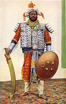 Photograph (hand-coloured), original dated 1898, of the lord high executioner of the former princely state of Rewah, Central India, with large executioner's sword (Tegha sword) The executioner.jpg