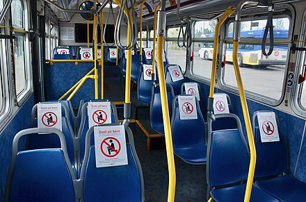 Signs in a TriMet bus promoting physical distancing during a temporary 10-passenger limit imposed in April TriMet bus with seats marked by "Don't sit here" signs during coronavirus pandemic, April 2020.jpg