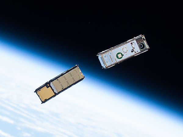 Two CubeSats orbiting around Earth after being deployed from the ISS Kibō module's Small Satellite Orbital Deployer