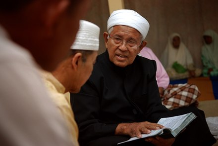 An Ustaz reading during a Malay wedding