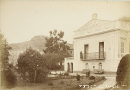 Stará fotografie vily s tvarovanými fasádami, trojúhelníkovým štítem, balkonem s Claire Salles-Eiffel a parkem.