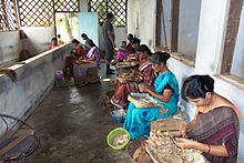 Factory workers hand cut the leaves using scissors and a metal stencil guide. After cutting a sufficient number of wrappers, they will move on to roll approximately 1,000 beedies each per day. Beedi factory near Nileshwaram, Kerala, India.jpg