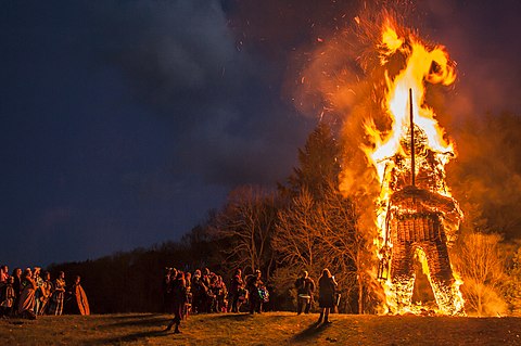 A burning bonfire of a towering 30 foot wickerman holding a sword. A crowd watches from below.