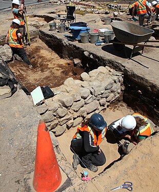 A half-excavated foundation stone wall during an archaeological excavation in Canada.