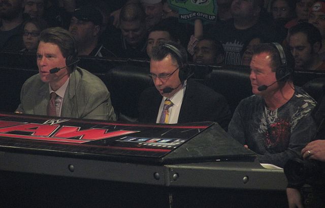 Cole (center) commentating on Raw with John "Bradshaw" Layfield (left) and Jerry Lawler (right) in January 2014