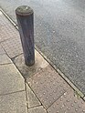 Wooden bollard painted grey, some paint is worn away