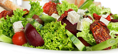 A garden salad with lettuce, sun-dried tomatoes, cherry tomatoes, beets, cucumber and feta cheese