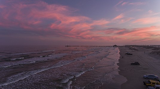 An aerial view of South Padre Island with people parked and driving on the beach at sunset