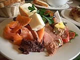 A gourmet antipasto platter with smoked salmon, smoked chicken (underneath), roast beef, pate[disambiguation needed], cabana sausage, brie-style cheese, cheddar-style goats milk cheese, Jensen's red washed rind cheese, olives, tapenade, rocket pesto (behind the dish), and tomato chutney