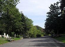 The approach road to the Woodvale cemetery, between high tree-lined banks, splits into three avenues which run through the valley between the graves. Approach Road at Woodvale Cemetery, Brighton.jpg