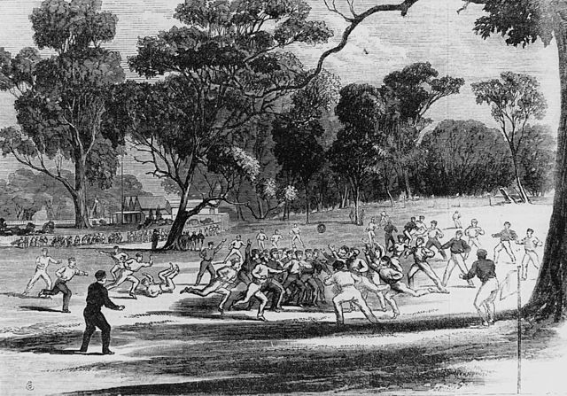 Engraving of a football match at the Richmond Paddock, 1866. The MCG and its first pavilion are visible in the background, as are kick-off posts, the 