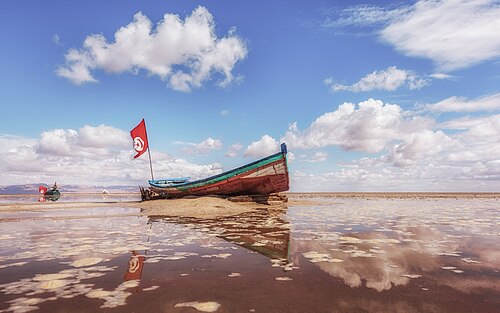 Barque sur une mer de sel et son reflet à Chott Jrid