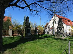 Boßdorf, zwei Kriegerdenkmale vor der Kirche. Im Hintergrund Eingang zum Pfarrhausgrundstück.