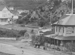 The bridge to Manitou House Hotel was built primarily for hotel traffic. The hotel was torn down and Memorial Park is now located to the left of the bridge in the photograph. A saloon to the right of the bridge is now the site of a bank.[3]