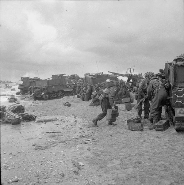 Troops of 3rd Division sheltering on Sword Beach on D-Day, with Bofors gun in background.