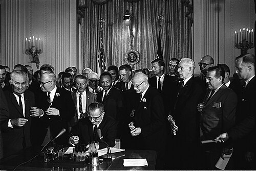 President Lyndon B. Johnson signs the 1964 Civil Rights Act as Martin Luther King, Jr. and others look on, July 2, 1964.