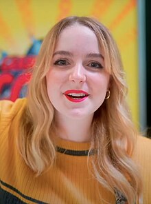 McKenna Grace smiling while wearing a yellow shirt at the 2023 German Comic Con, in Dortmund