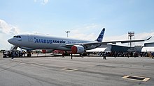 A A330-200F in Airbus's white and blue livery on display under a partly cloudy but otherwise clear sky. The engine inlets are covered.