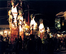 Twenty-foot illuminated caterpillars — animated pageant sized puppets designed by Alex Kahn of Superior Concept Monsters — transform Manhattan's Greenwich Village in 1998 (the former Twin Towers are prominently seen in the background)