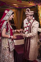 A Hindu Indian wedding, with the groom wearing sherwani and pagri turban, while the bride in a sari.