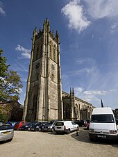 A church built in Gothic style with the tower in the centre of the picture and the main body of the church extending to the right