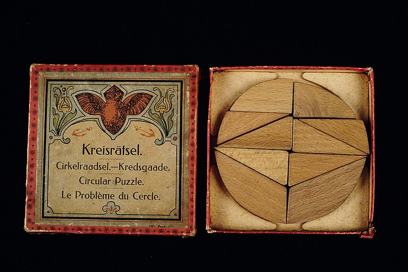 File:Tangramspel “Kreisrätsel Cirkelraadsel Kredsgaade Circular Puzzle Le Problème du Cercle” in rood doosje houten stukken en boekje met voorbeelden, objectnr 71642.JPG