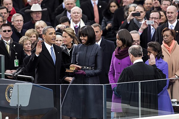 Michelle Obama (center) at Barack Obama's second inauguration, wearing a Browne silk jacquard coat and dress in a navy checked pattern based on "a men
