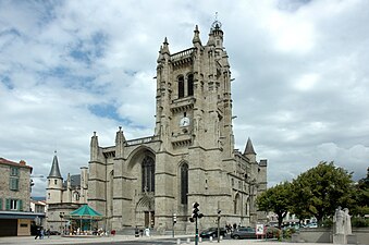 Photographie couleur d'une église gothique surmontée d'une tour-clocher à l'angle le plus proche