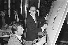 Photo en noir et blanc de deux dessinateurs dessinant leurs personnages sur des tableaux de conférence.
