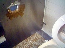 A glory hole is visible in the wall (left) in this toilet in California. Glory hole in washroom (155966507).jpg