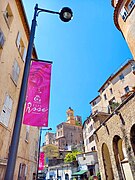 Une belle tour horloge vue depuis le boulevard Gambetta à Grasse, avec le clocher de la cathédrale Notre-Dame du Puy de Grasse en arrière plan.