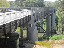 Wrought-iron spans of the Prince Alfred Bridge at Gundagai, N.S.W., viewed from the southern bank (Oct. 2019). Cast-iron cylindrical casings of the supporting columns were cast in 1865-1866 at Fitzroy Iron Works, from iron smelted there. Gundagai Prince Alfred Bridge from southern bank (Oct. 2019).jpg