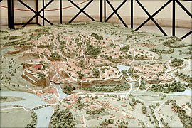 Photographie en couleurs d'une maquette représentant un site de collines près d'un fleuve et quelques bâtiments.