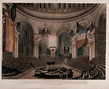 Nelson's coffin in the crossing of St Paul's, during the funeral service; the dome hung with captured French and Spanish flags Nelson State Funeral.jpg