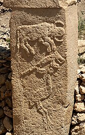 Photographie d'un pilier de pierre beige sculpté de trois animaux.