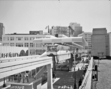 A monorail train departs from the covered south terminal as seen from a nearby rooftop