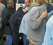 Taxi drivers concealing their faces as they take the customary perp walk before the news media. The perp walk is a well-known feature of New York's criminal justice system. Taxi driver perp walk.jpg