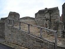 The seated figure is thought to be that of Christ or of King Ethelbald and is possibly from the west front of the Croyland Abbey. Trinity Bridge (Crowland, Lincolnshire, England) seated figure.JPG