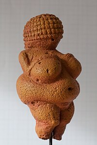Small statue, carved in stone, of a nude obese woman with her face veiled
