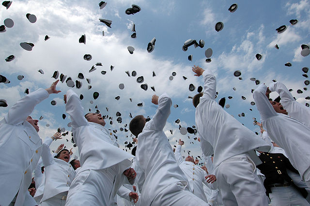 Выпускники Военно-Морской Академии США 2005 года празднуют окончание и бросают мичманские фуражки в воздух.