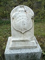 Photograph of gravestone with military shield marker with the name Henry in the middle.