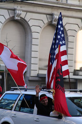 People celebrating Kosovo's declaration of independence in Lausanne, Switzerland, with their car holding the Swiss, Albanian, and American flags