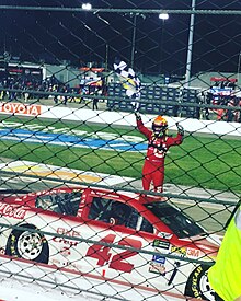 Larson waving the checkered flag in the air after winning the 2017 Federated Auto Parts 400 Larson thrusts the checkered flag in the air after winning the 2017 Federate Auto Parts 400.jpg