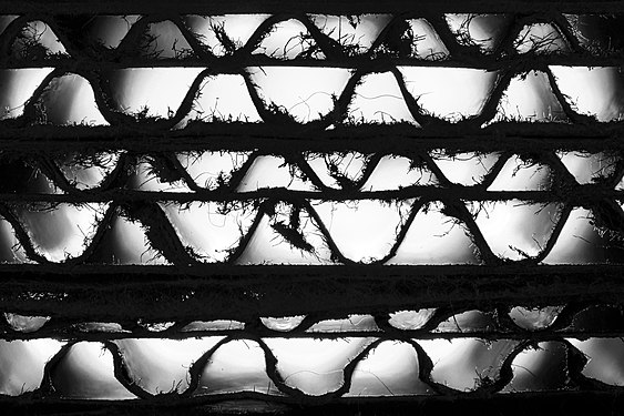 Backlit longitudinal view through stack of cardboard sheets - focus on serrated fibres at front edge