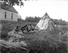 Mi'kmaq peoples weaving baskets next to a lodge of tar and canvas; 1941 Mikmaq braiding baskets, Indian Island (27750).jpg