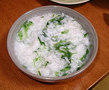 Les grains de riz blanc conservent encore leur forme dans une bouillie de bouillon mélangée à des herbes vertes