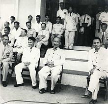 Hồ Chí Minh watching a football game in his favorite fashion, with his closest comrade Prime Minister Phạm Văn Đồng seated to Hồ's left (photo right) (Source: Wikimedia)