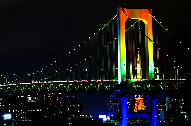 City bridge lit up at night with the colors of the rainbow.