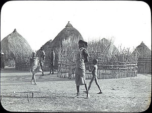 Village du début du XXe siècle, avec des huttes au toit de chaume et des passants